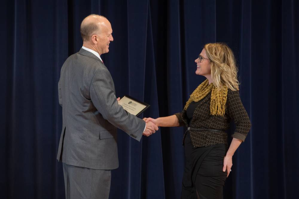 Student shaking hands with Dean Potteiger as they receive their award